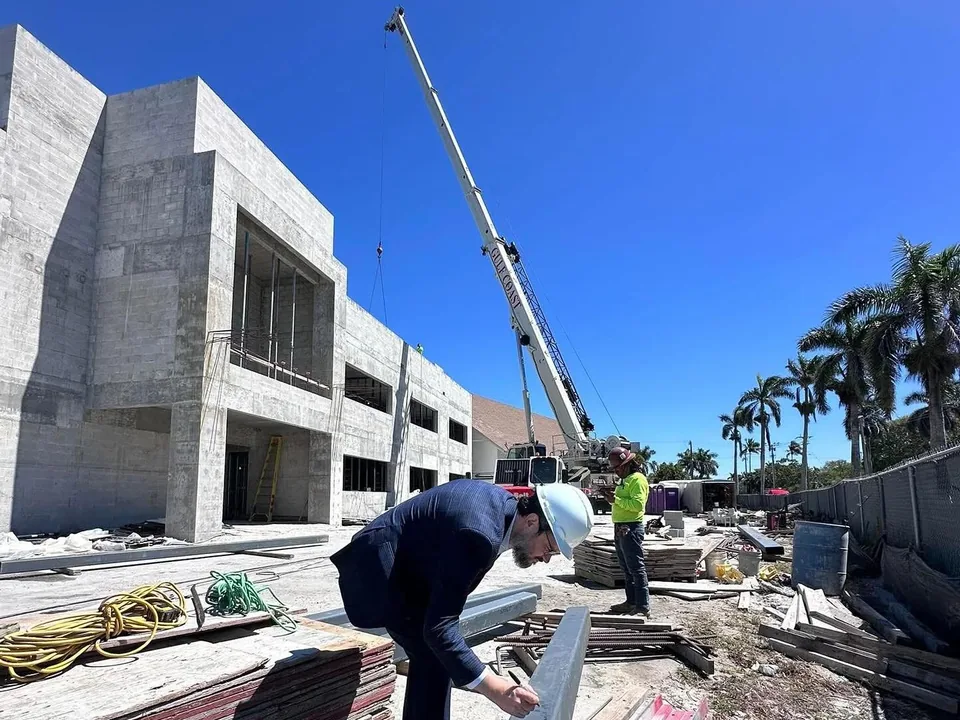 The new building’s concrete shell under construction, with a crane and a steel beam being signed