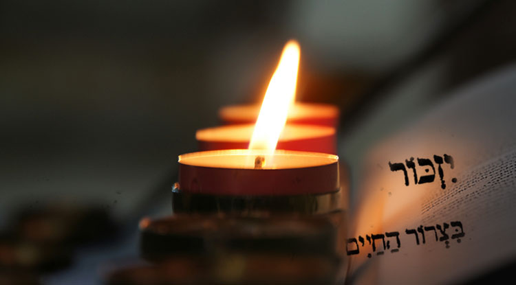 Memorial candle beside an open Yizkor prayer book