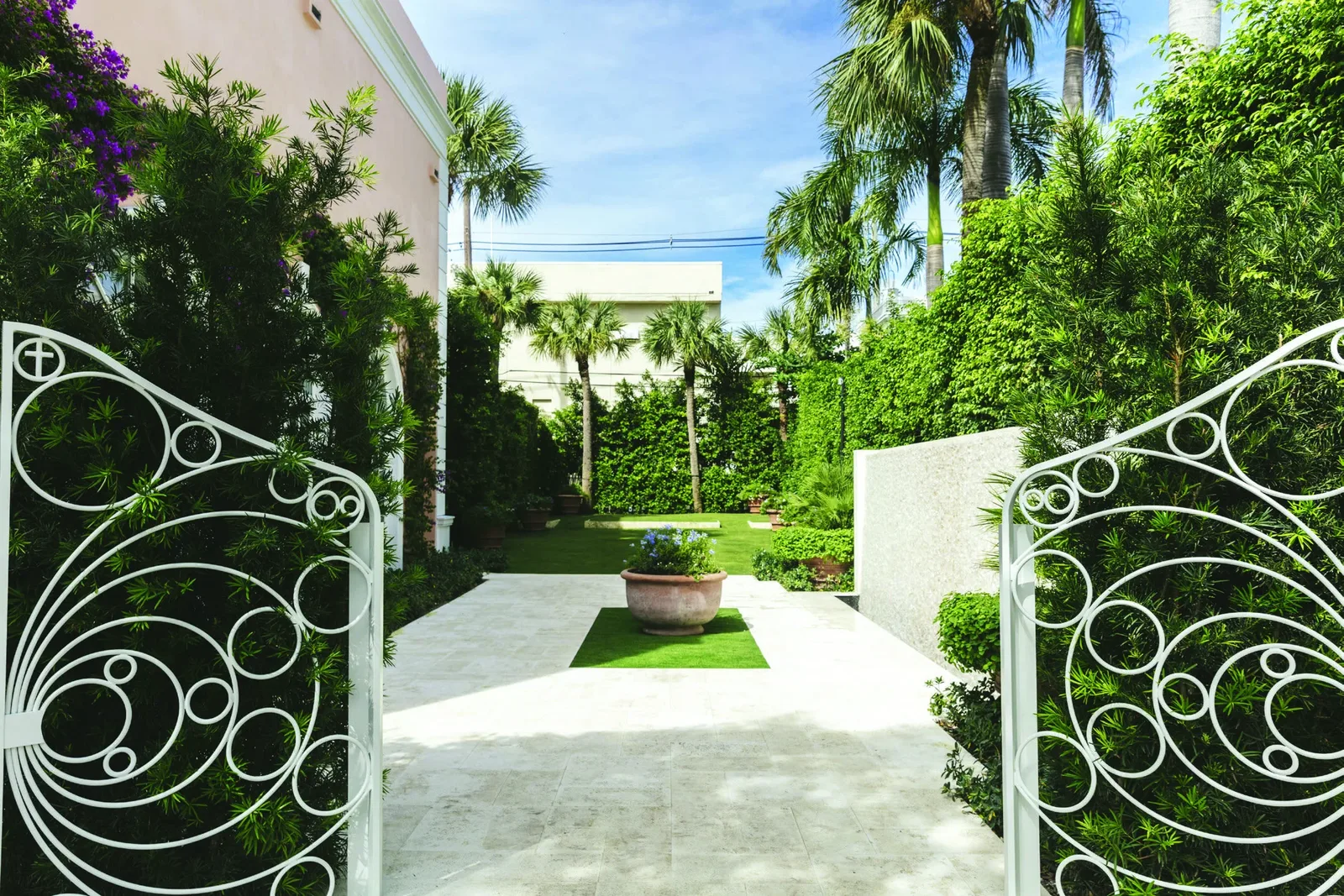 The open gates and lush East Garden at The Colony Palm Beach